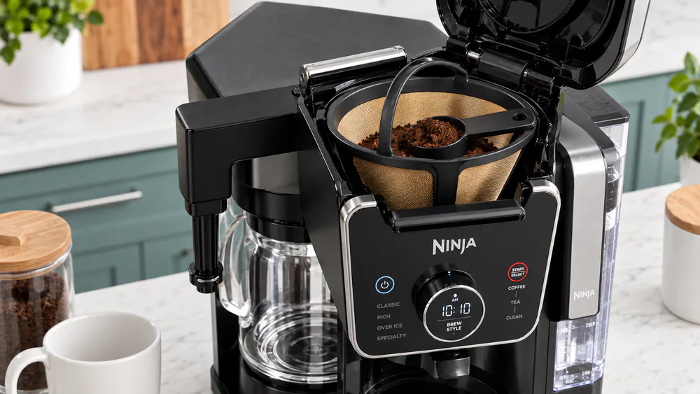 The permanent gold-tone mesh filter seated in the Ninja CFP307 brew basket, a small pile of coffee grounds inside