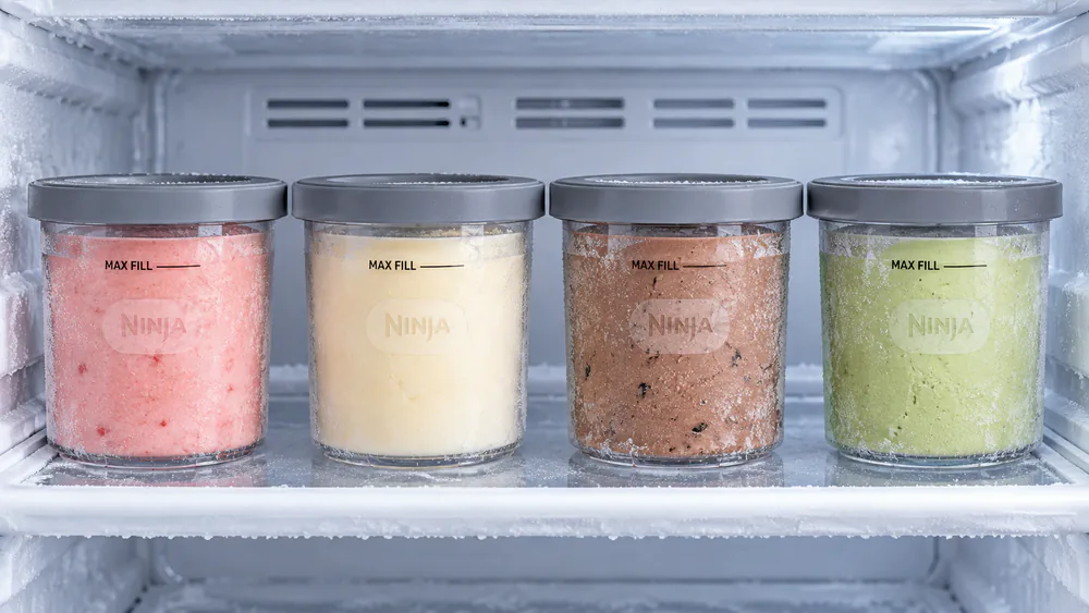 A home freezer stocked with a rotation of four pre-frozen Ninja Creami pints, ready for the evening spin.