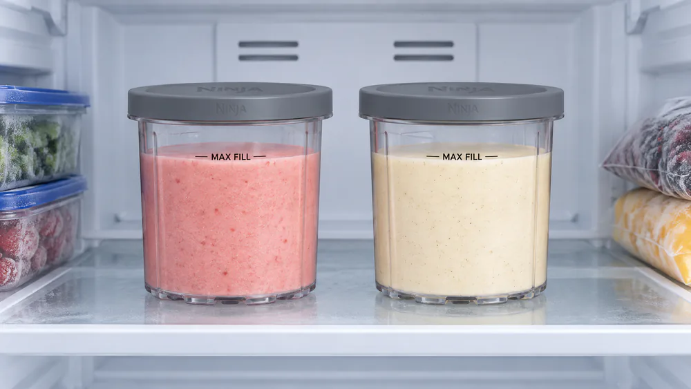 Two Ninja Creami pints freezing flat on a freezer shelf.
