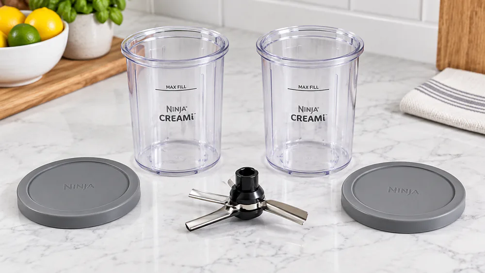 Two Ninja CREAMi 16 oz pint containers and the Creamerizer paddle on a counter.
