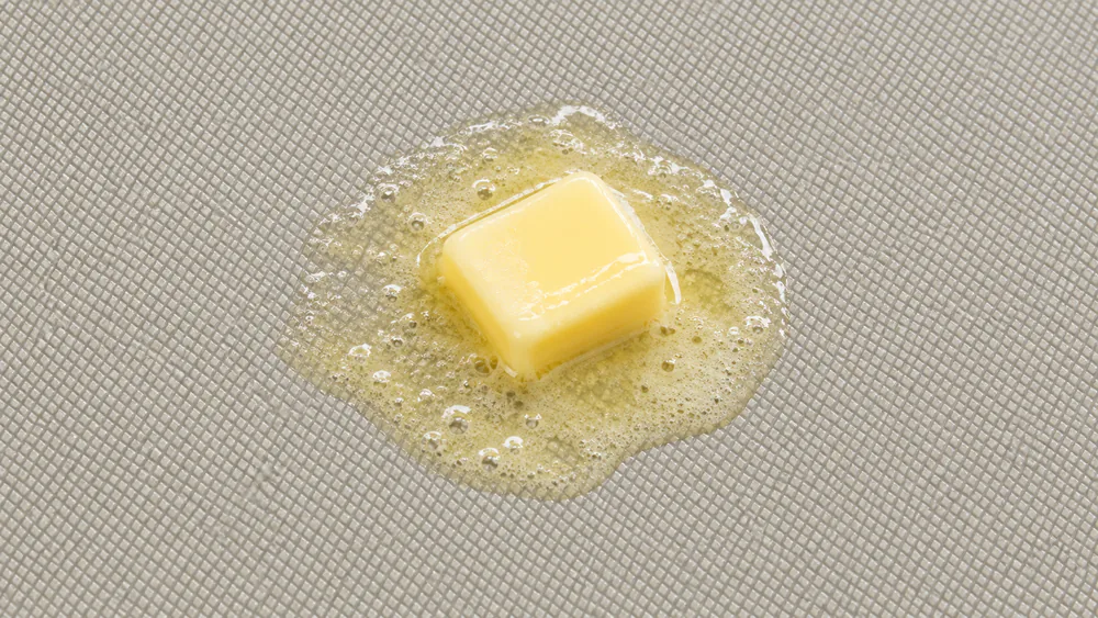 The diamond-textured ceramic cooking surface of a Presto 07062 griddle, with a thin film of butter melting near the center