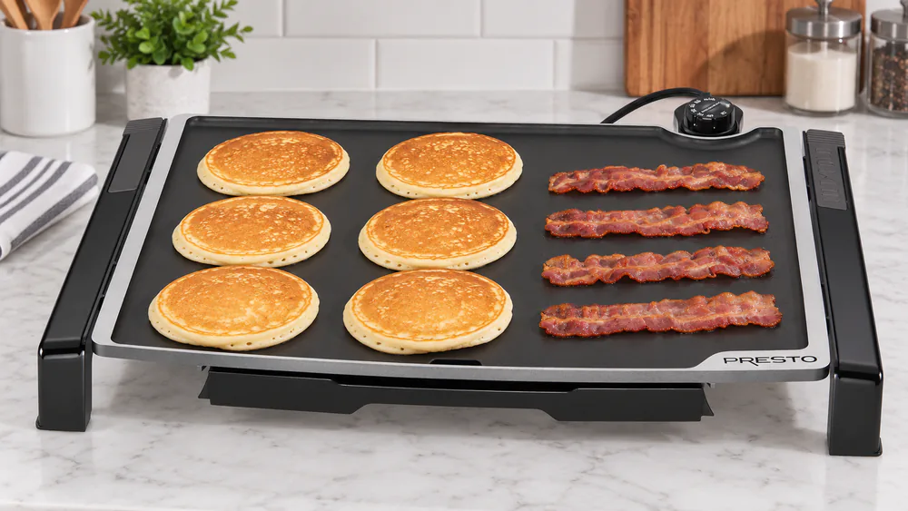 Pancakes and bacon cooking side by side on the Presto 07073 19-inch ceramic griddle surface