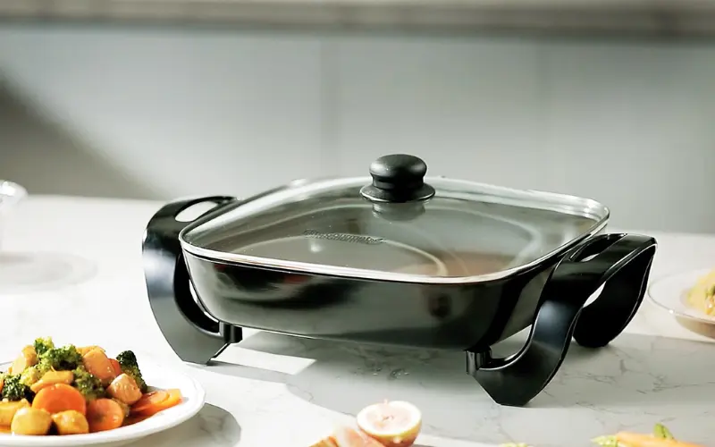 a black square pan with a glass lid on a white surface