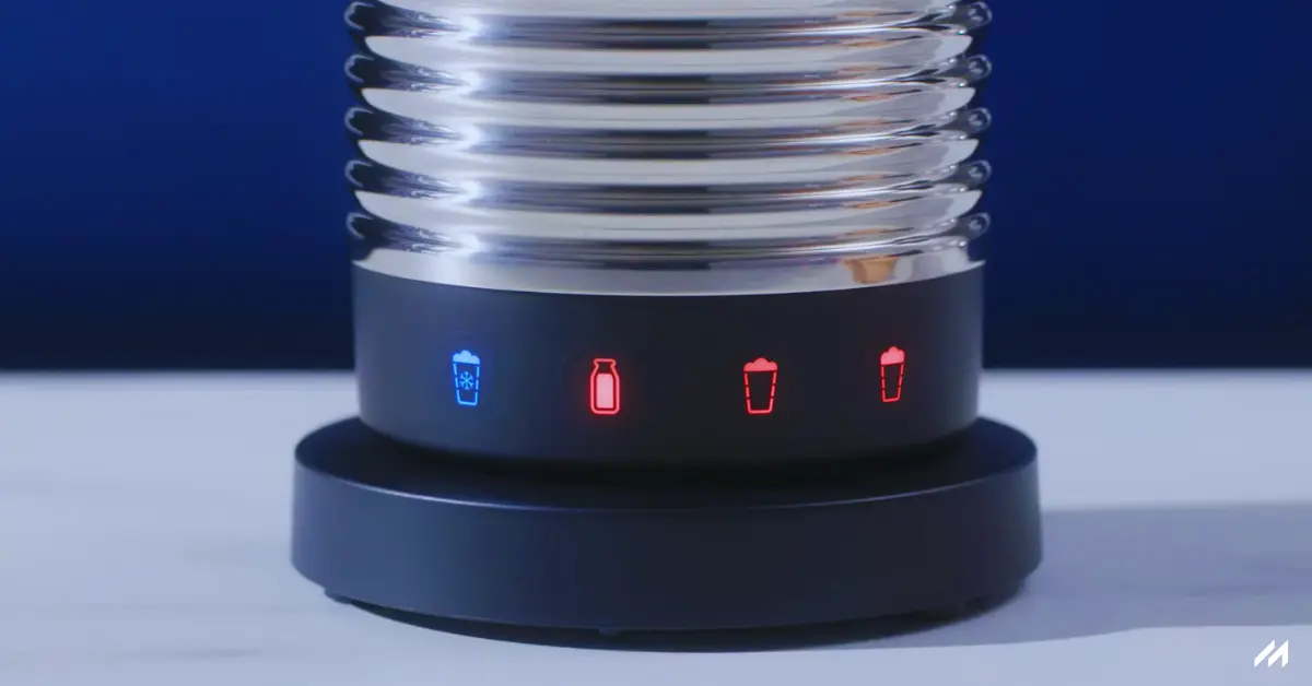 The image shows the control base of the Nespresso Aeroccino 4, with four illuminated buttons indicating cold and hot frothing modes. The sleek stainless steel body is visible in the background, showcasing its modern design.