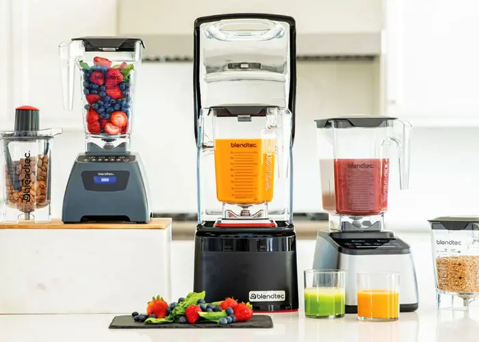 Blendtec Professional 800 - Blender Blendtec Professional 800 blender with sound enclosure blending fruit smoothie on a kitchen counter alongside jars and ingredients.