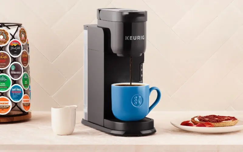 Keurig K-Express Single Serve Coffee Maker Keurig K-Express single-serve coffee maker brewing coffee into a blue mug on a kitchen countertop.