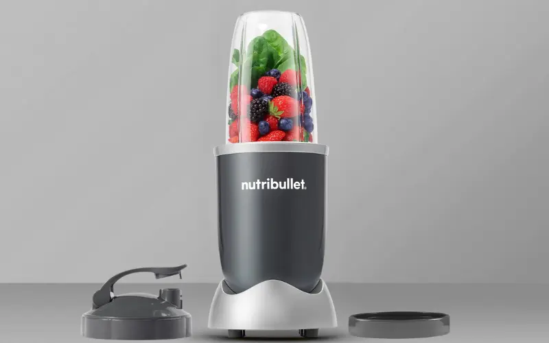 Nutribullet 600 Blender with berries, spinach, and blending accessories.