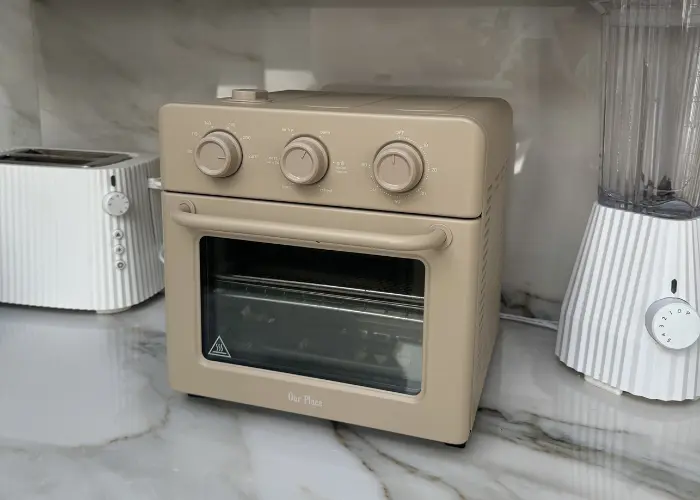Our Place Wonder Oven Review Our Place Wonder Oven countertop air fryer toaster oven with beige retro design on kitchen counter