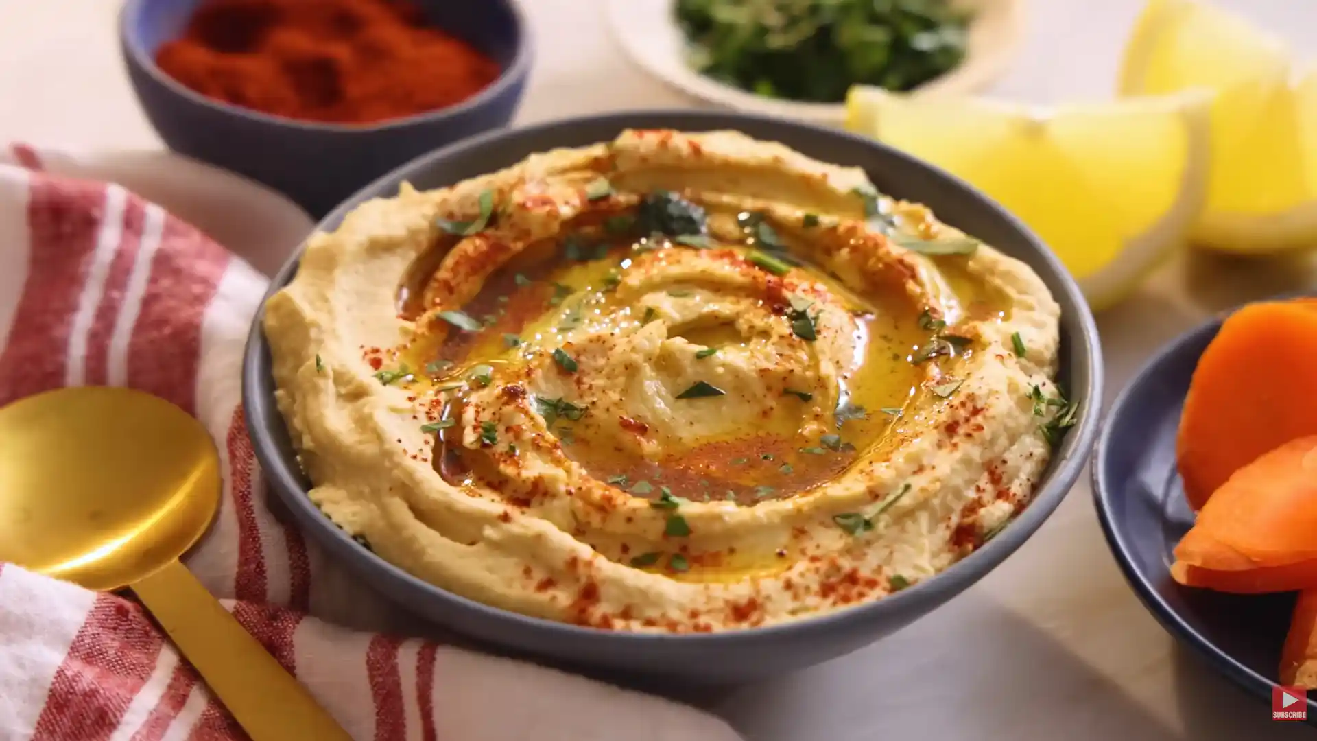 How to Make Hummus Recipe Creamy homemade hummus Recipe topped with olive oil, paprika, and fresh herbs, served with lemon wedges and vegetables.